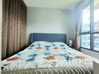 Cozy bedroom with floral bedding and large window in modern apartment