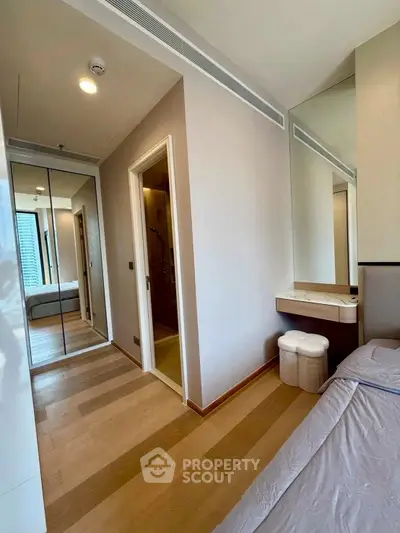 Modern bedroom with mirrored closet and ensuite bathroom in a stylish apartment.