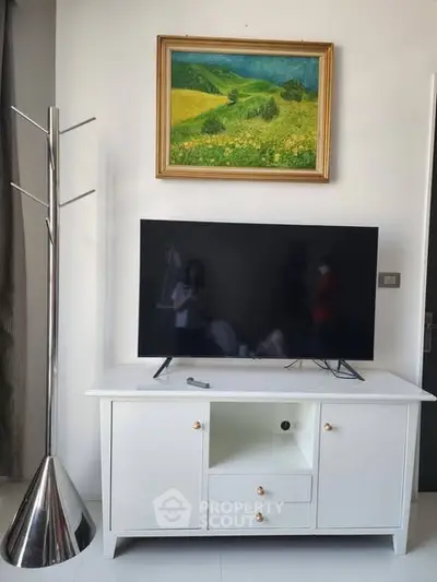 Modern living room with sleek TV stand and vibrant landscape painting.