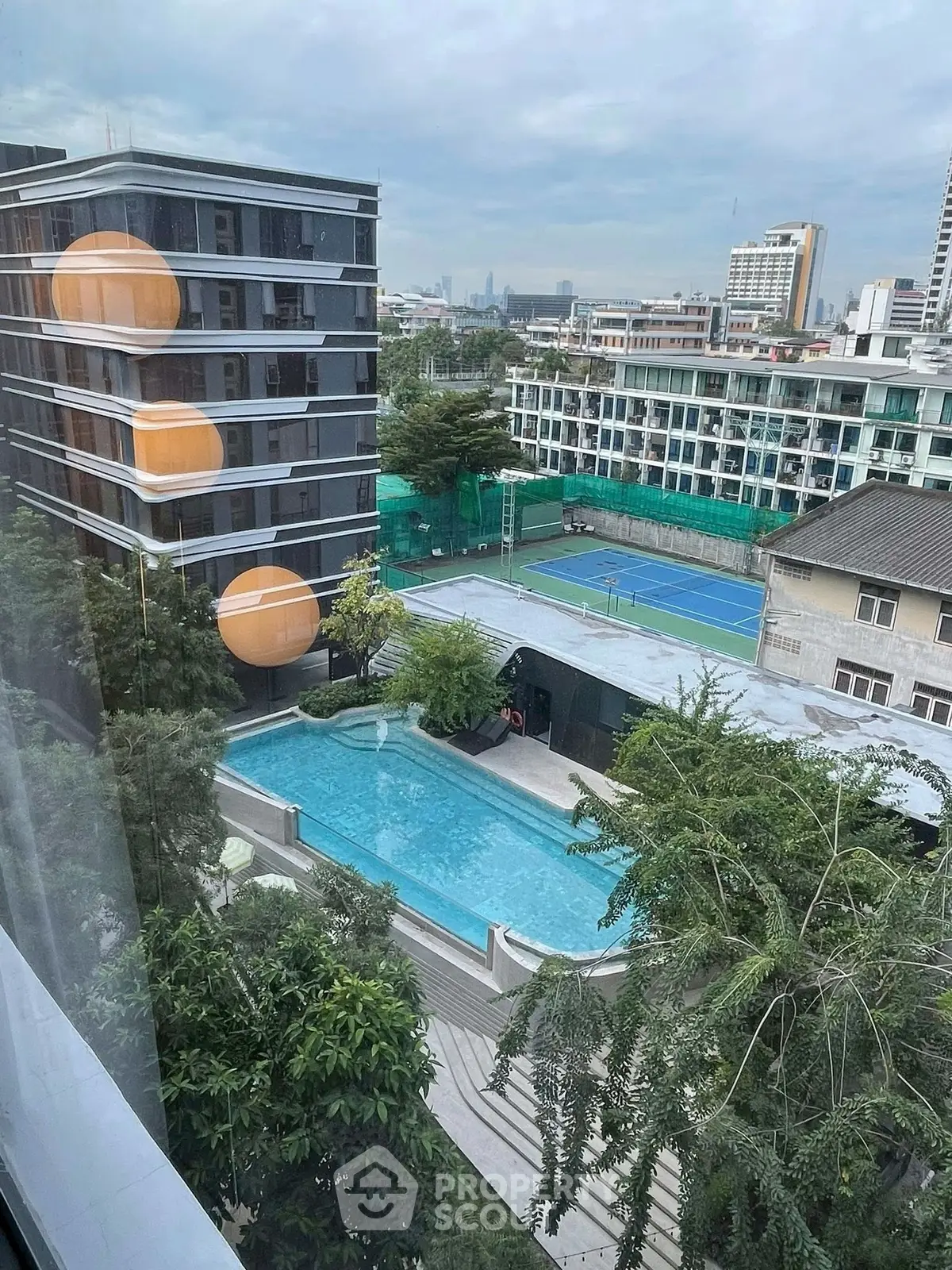 Stunning urban view with pool and tennis court in modern residential complex.