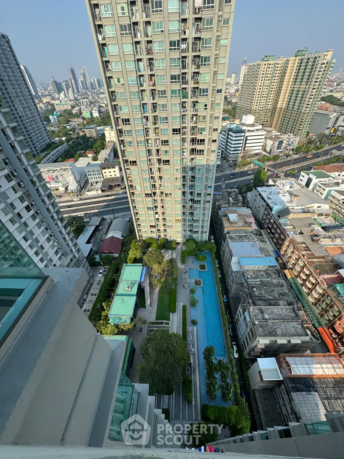 Stunning aerial view of modern high-rise building with pool and cityscape backdrop.