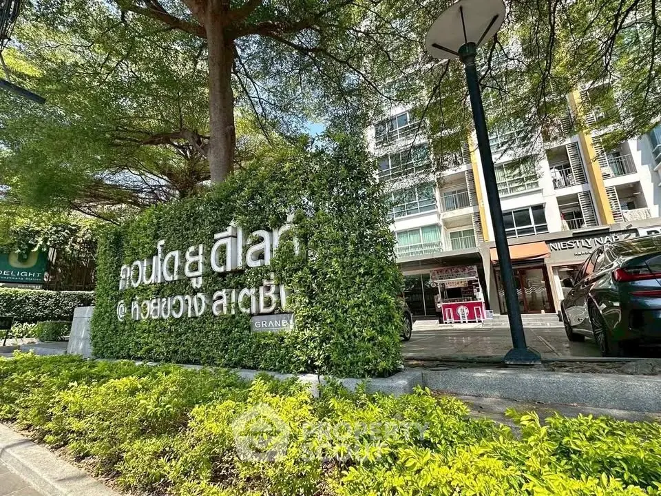 Modern building exterior with lush greenery and clear signage in urban setting.