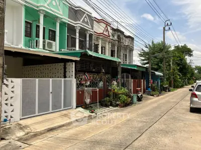 Charming row of colorful townhouses with lush greenery on a quiet street, perfect for family living.