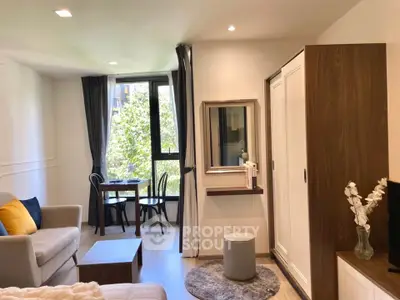 Charming studio apartment with cozy living area and large window view.