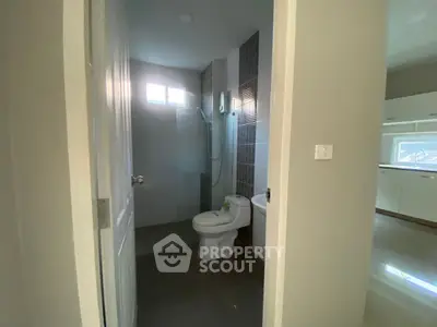 Modern bathroom with glass shower and adjacent kitchen view