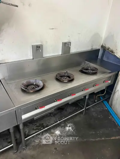 Commercial kitchen with stainless steel gas stove and three burners, ideal for restaurant use.