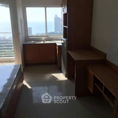 Modern studio apartment with ocean view, featuring compact kitchen and natural light.