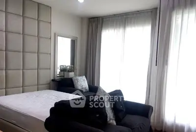 Elegant bedroom with plush bed and cozy seating area by large window.