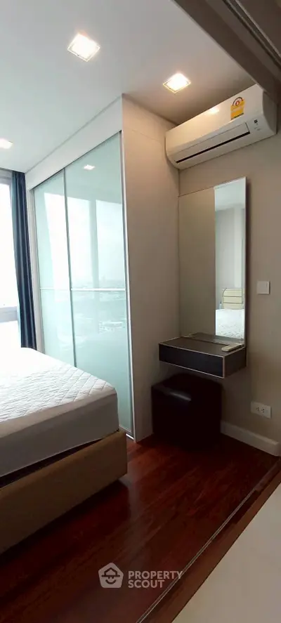 Modern bedroom with large window and air conditioning unit, featuring sleek design and natural light.