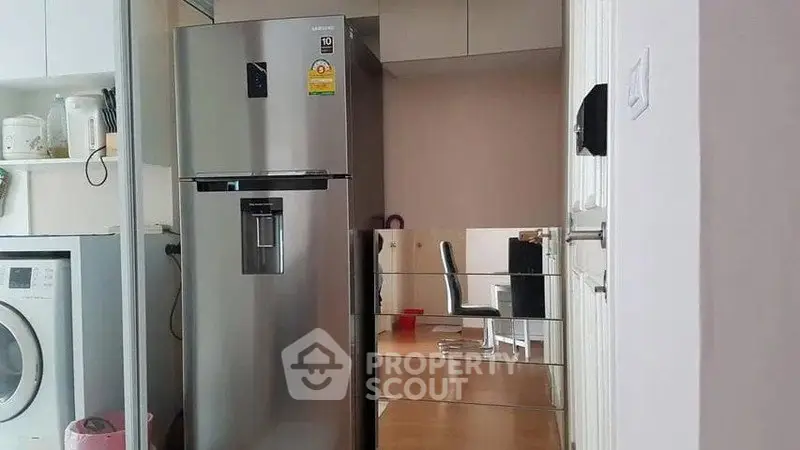 Modern kitchen with stainless steel fridge and washing machine, reflecting a sleek interior design.