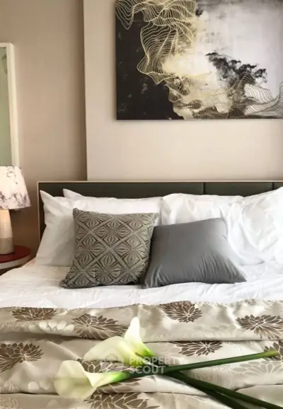 Elegant bedroom with stylish decor and cozy bedding, featuring modern art and soft lighting.