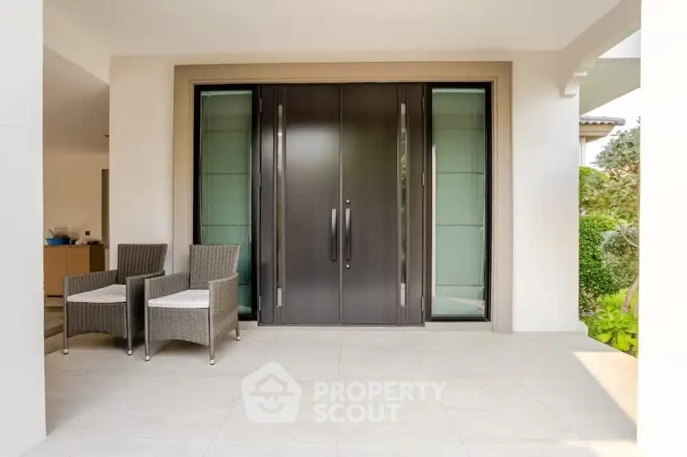 Elegant entrance with modern double doors and cozy outdoor seating.