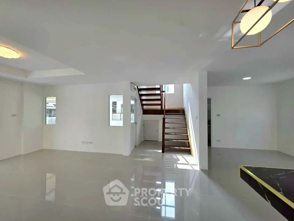 Spacious modern living area with sleek staircase and glossy tile flooring