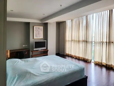 Spacious bedroom with large windows and modern decor in a luxurious apartment.