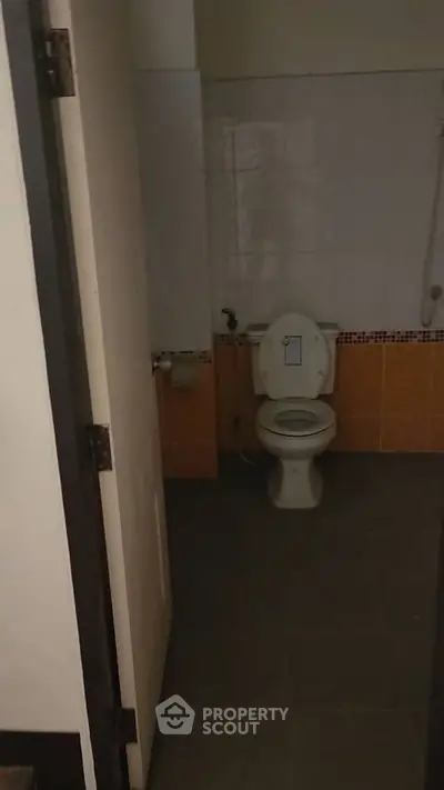 Dimly lit bathroom with toilet and tiled walls, basic and functional.