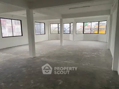 Spacious open-plan interior with large windows and concrete flooring, ideal for customization.