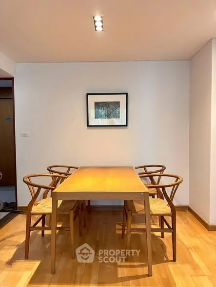 Modern dining area with wooden table and chairs, featuring minimalist decor and warm lighting.