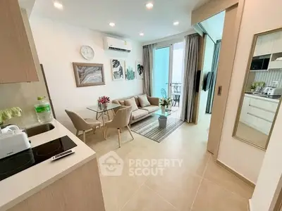 Modern open-plan living room with kitchen and balcony access, featuring stylish decor and natural light.