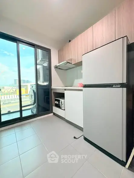 Modern kitchen with sleek appliances and balcony view in urban apartment