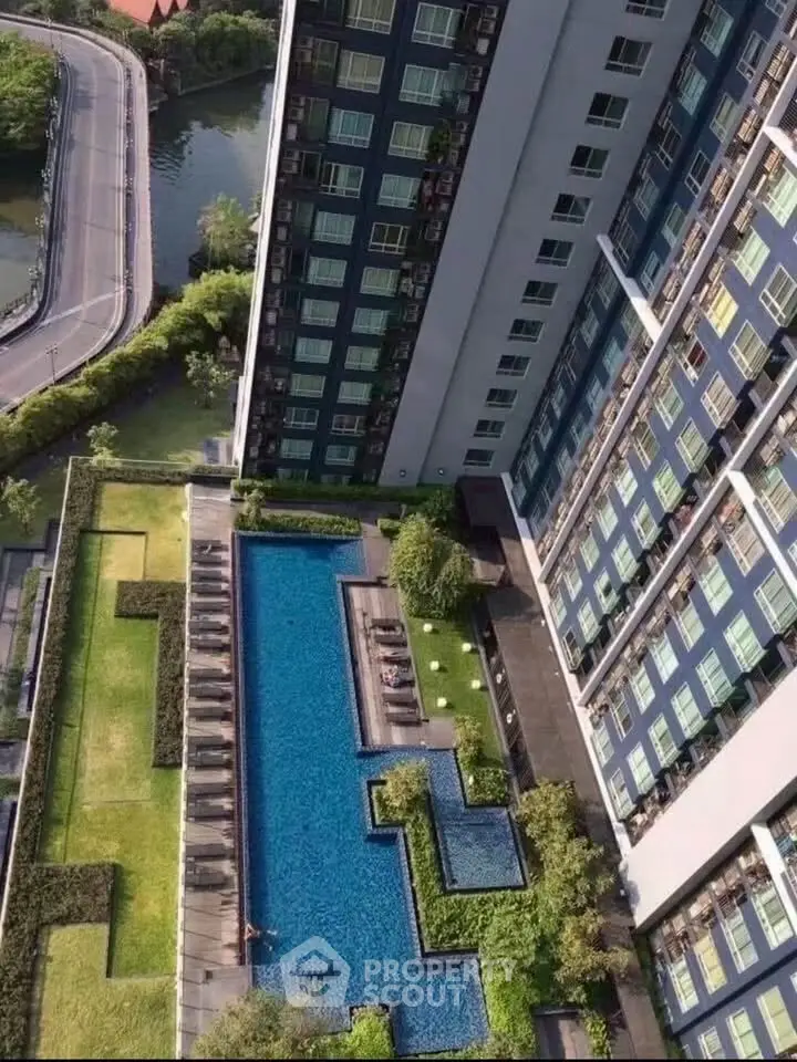 Stunning aerial view of modern apartment building with luxurious swimming pool and lush greenery.