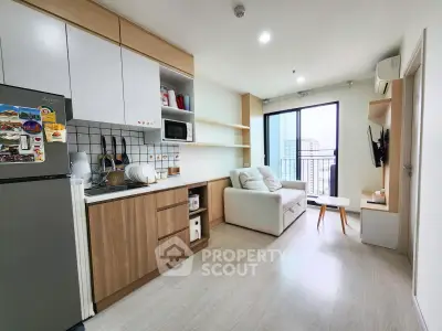 Modern open-layout living room with kitchen, featuring sleek cabinetry and a cozy sofa, perfect for urban living.