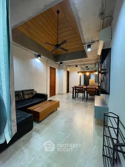 Modern industrial-style living room with sleek furniture and unique ceiling design.