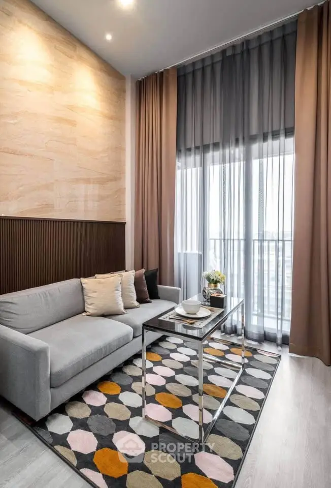 Modern living room with high ceilings and stylish decor, featuring a cozy sofa and large windows.