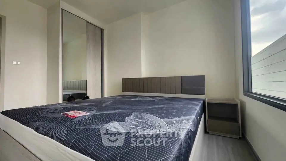 Modern bedroom with large window and stylish decor in a contemporary apartment.