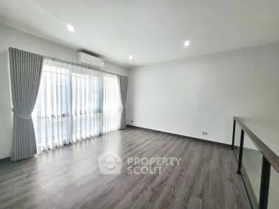 Spacious empty living room with large windows and modern flooring.