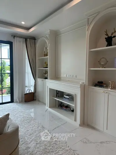 Elegant living room with built-in shelves and large window, featuring modern decor and plush carpeting.