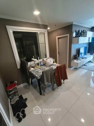 Modern living room with sleek furniture and stylish decor, featuring a cozy dining area and entertainment setup.