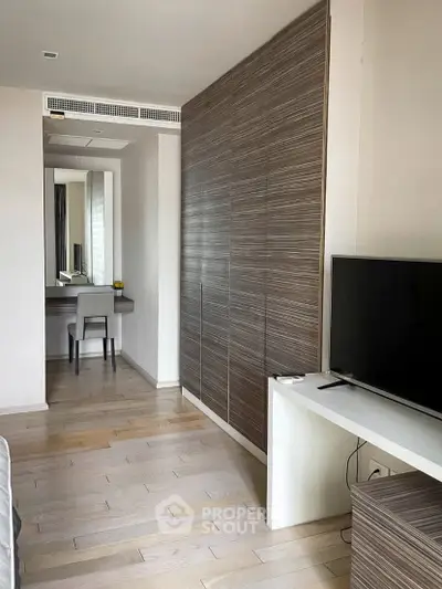 Modern bedroom with sleek wooden wardrobe and TV, featuring a cozy study nook.