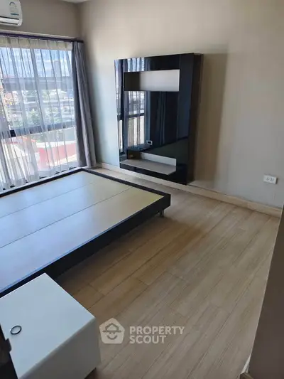 Modern bedroom with large window and sleek wooden flooring