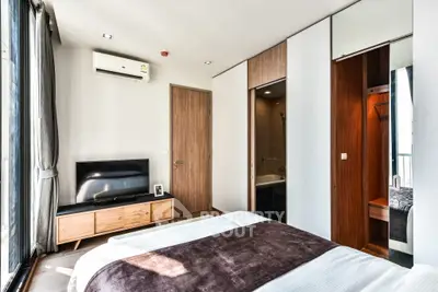 Modern bedroom with sleek design, featuring a wall-mounted TV, air conditioning, and a stylish ensuite bathroom.
