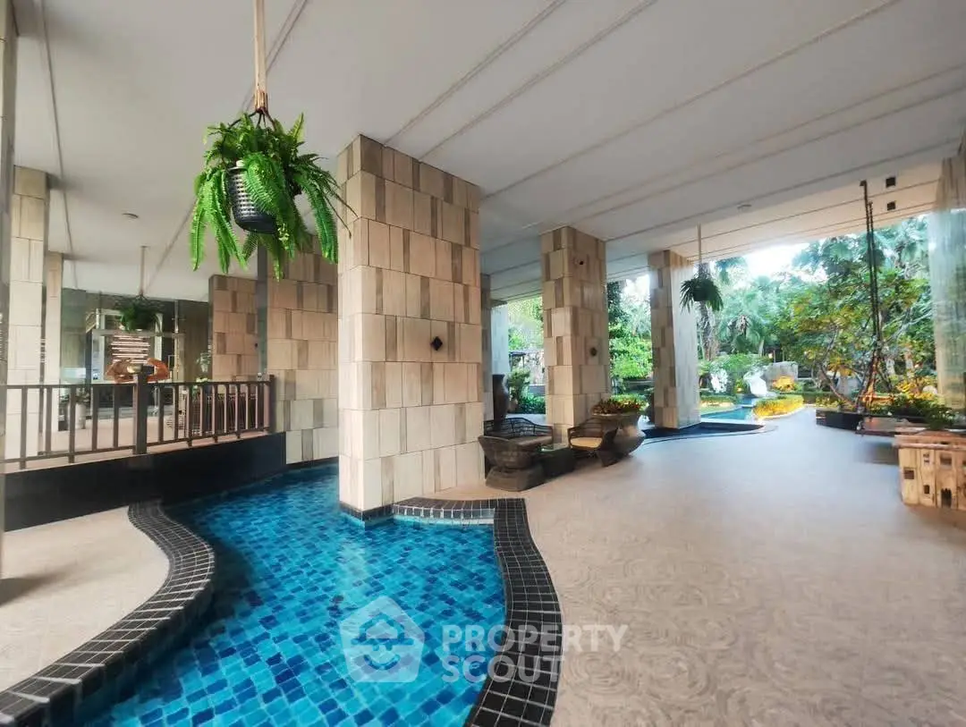 Luxurious building entrance with elegant water feature and lush greenery