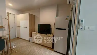 Modern living room with sleek furniture and appliances, featuring a TV and refrigerator for comfortable living.