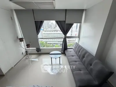 Modern living room with city view, featuring sleek gray sofa and glass coffee table.