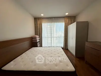 Spacious bedroom with large window and modern furnishings in a cozy apartment.