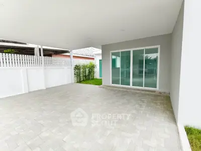 Spacious covered patio with sliding glass doors and garden view