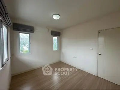 Spacious empty room with large windows and wooden flooring, perfect for customization.