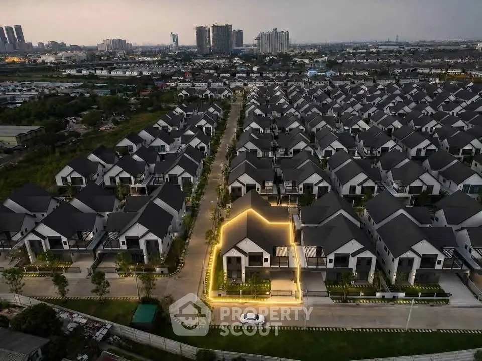 Aerial view of modern suburban housing development with uniform architecture and illuminated house outline.