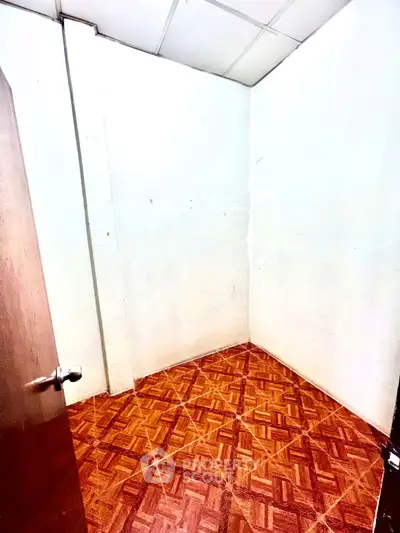 Compact room with wooden flooring and white walls, ideal for storage or small office space.