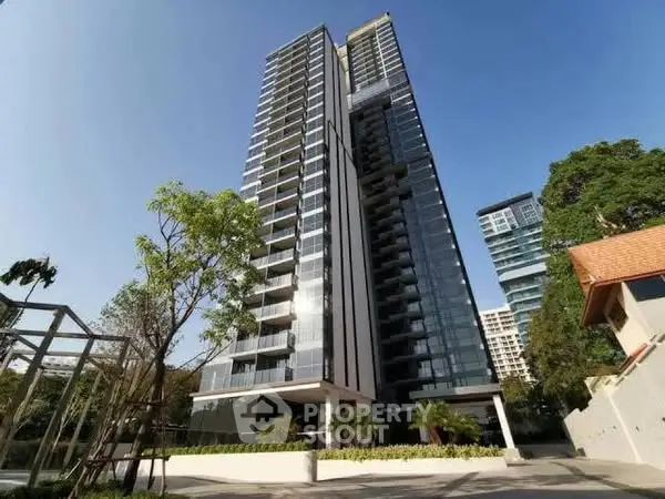 Modern high-rise building with sleek glass facade and lush greenery
