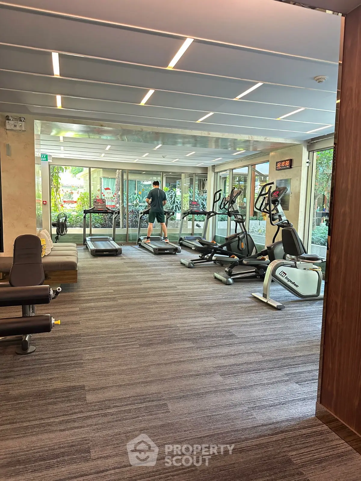 Modern gym with cardio equipment and garden view in luxury residential building.