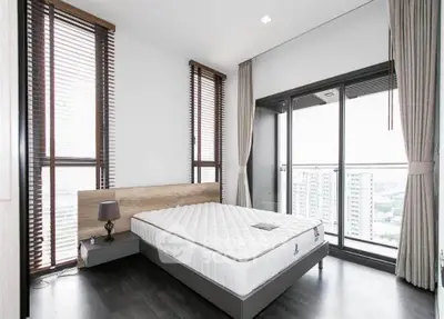 Modern bedroom with floor-to-ceiling windows and balcony view in high-rise apartment.