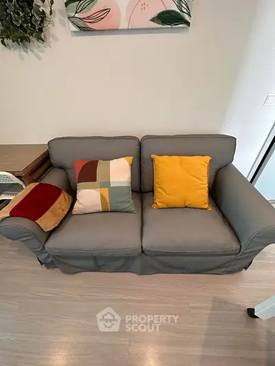 Cozy living room with stylish gray sofa and colorful cushions, perfect for relaxation and comfort.