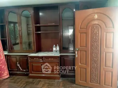 Spacious room with elegant wooden cabinetry and ornate door, perfect for stylish living.