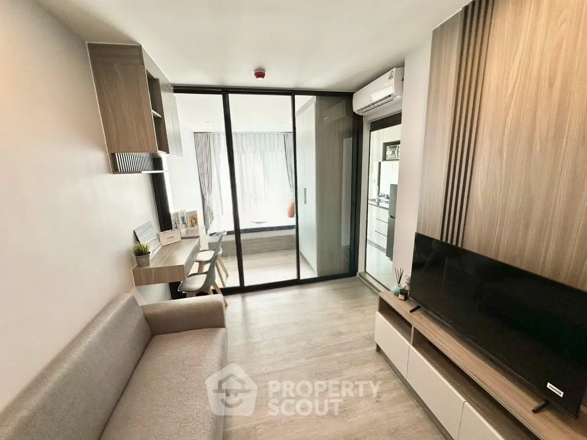Modern living room with sleek design and glass partition, featuring a cozy sofa and wall-mounted TV.