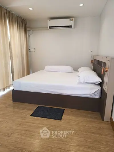 Modern bedroom with wooden flooring and air conditioning in a stylish apartment.
