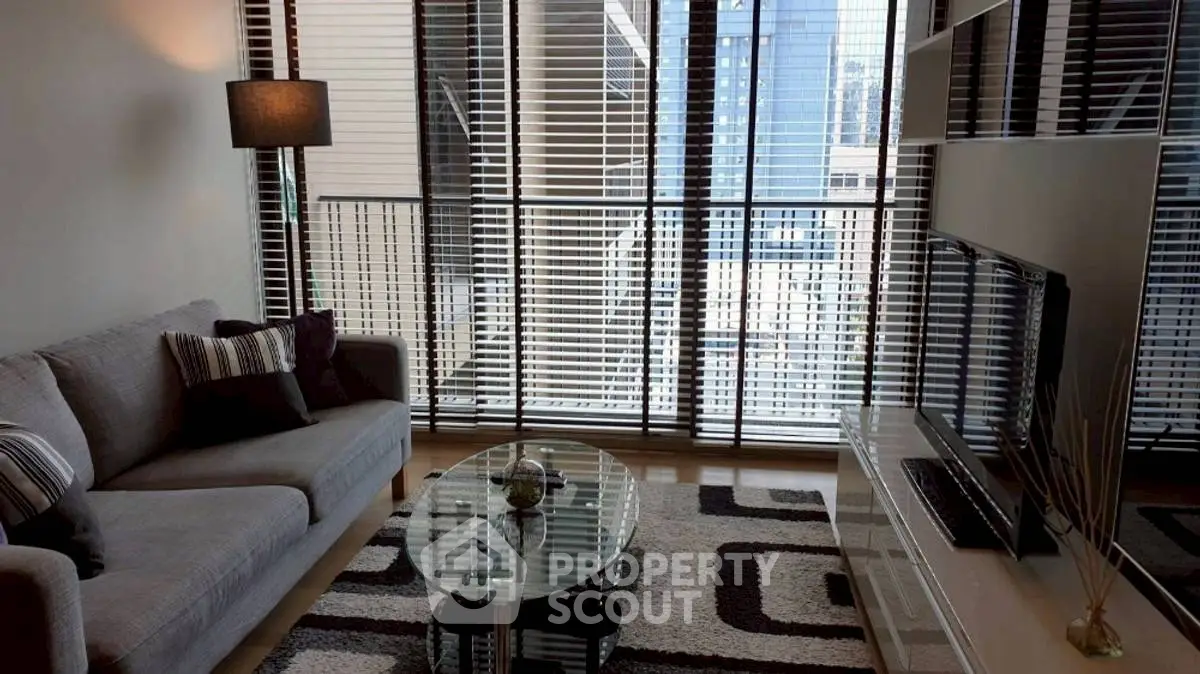 Modern living room with stylish decor and city view through large windows.